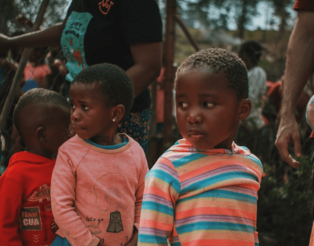 Children smiling outdoors at an A'khira Charity community program in Uganda